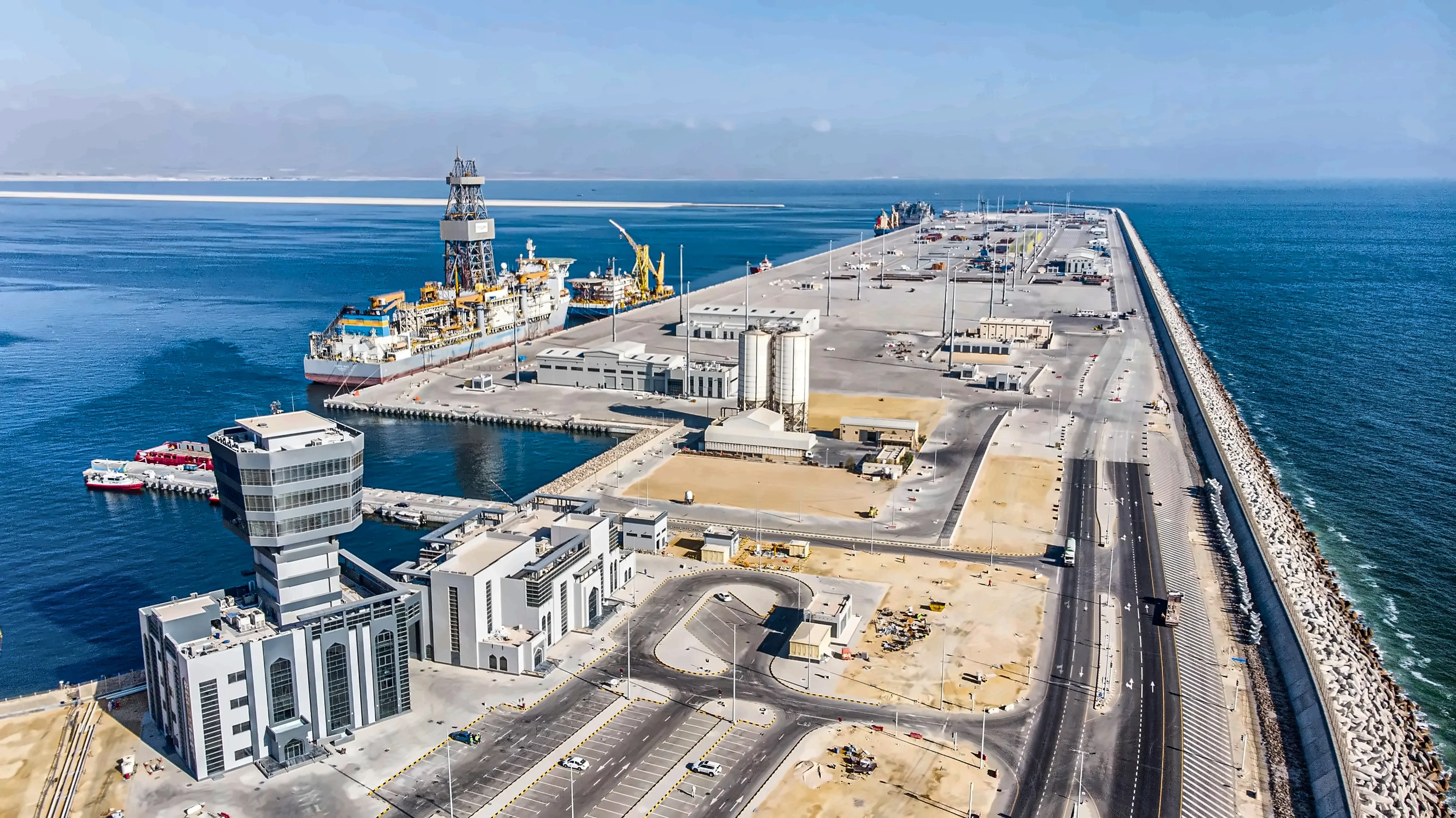 Aerial view of an Omani port with ships alongside a long breakwater
